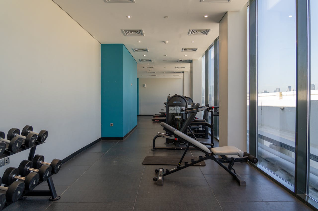 services-01 Spacious gym with exercise machines and dumbbells, perfect for bodybuilding and fitness enthusiasts.